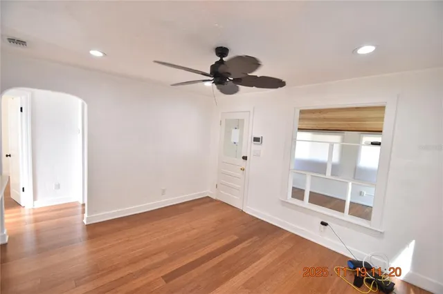 a view of empty room with wooden floor and fan