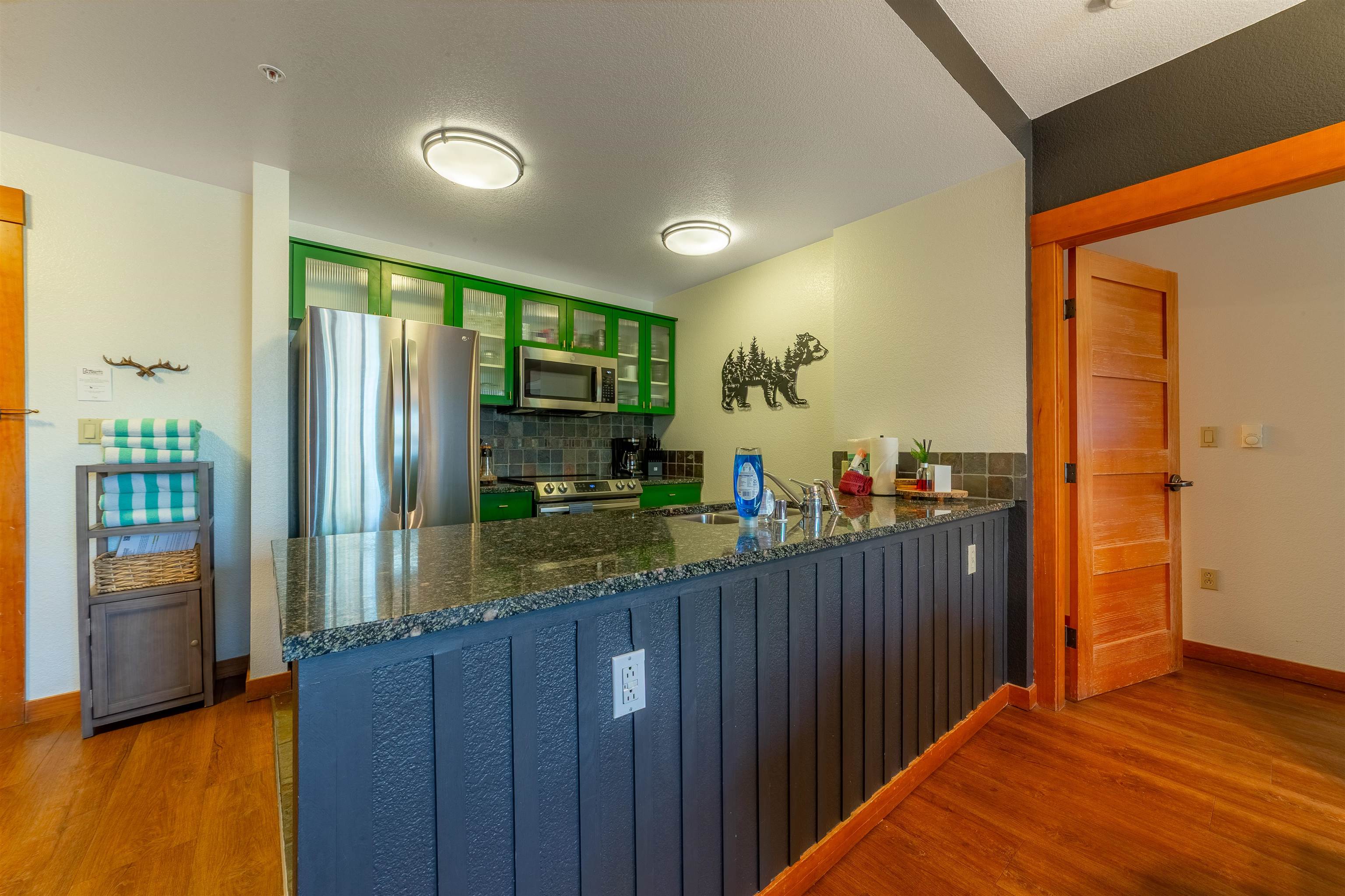 6201 Minaret Road, Unit 2221 Mammoth Lakes, CA 93546 - Photo 9 of 44 Kitchen featuring stainless steel appliances, solid surface countertops, a tile backsplash, and wood-finish flooring