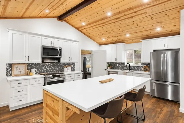 a kitchen with stainless steel appliances a stove a sink dishwasher a refrigerator white cabinets and wooden floor