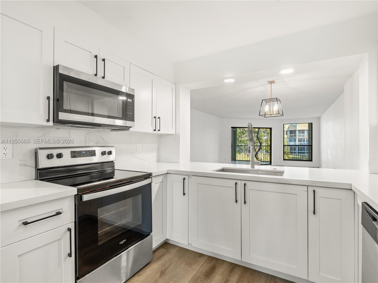 7547 Fairfax Drive, Unit 210 Tamarac, FL 33321 - Photo 12 of 38 a kitchen with cabinets stainless steel appliances and wooden floor