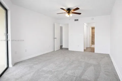 an empty room with a chandelier fan and windows