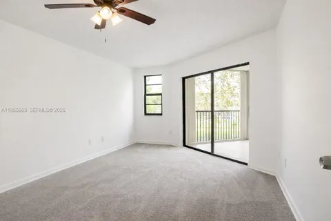 an empty room with chandelier fan and windows