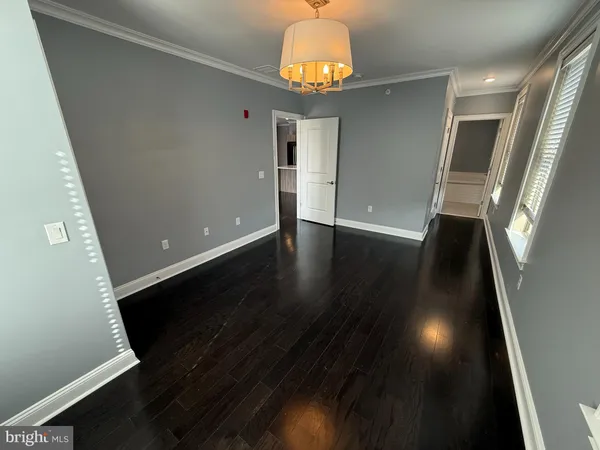 an empty room with wooden floor and chandelier
