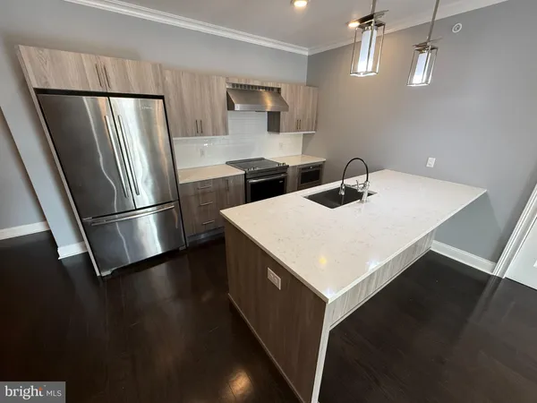 a kitchen with kitchen island a sink a refrigerator and wooden floor