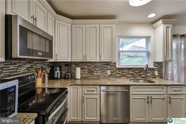 a kitchen with granite countertop a sink stainless steel appliances and cabinets
