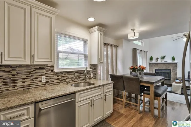 a kitchen with granite countertop a sink stainless steel appliances and white cabinets