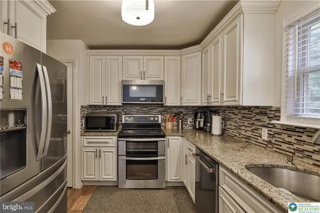 a kitchen with granite countertop a refrigerator stove and microwave
