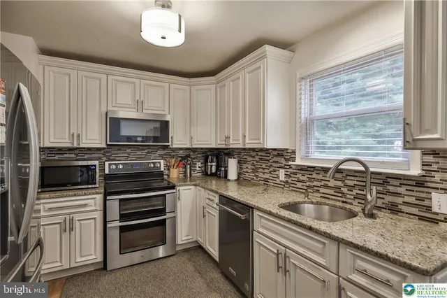 a kitchen with stainless steel appliances granite countertop a refrigerator and cabinets