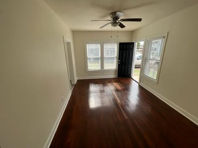 a view of empty room with wooden floor and fan