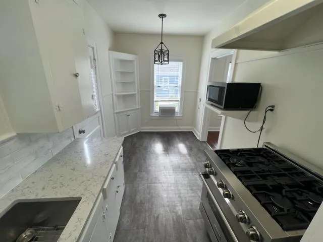a kitchen with granite countertop a stove and a wooden floor