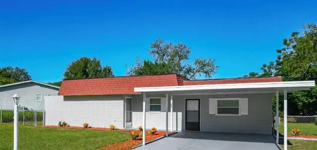 a view of a white house with a big yard and potted plants