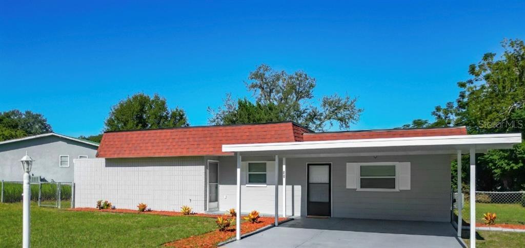 a view of a white house with a big yard and potted plants
