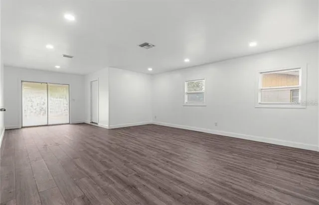 an empty room with wooden floor and windows