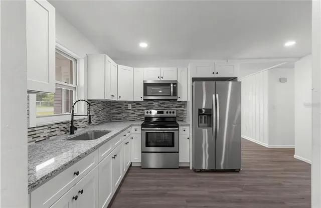 a kitchen with stainless steel appliances granite countertop a refrigerator and a stove top oven
