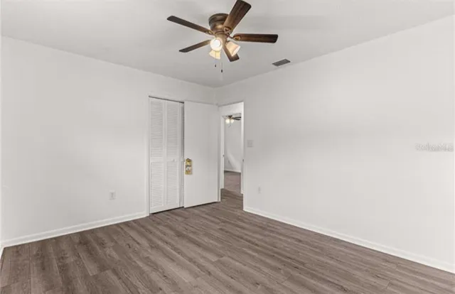 an empty room with wooden floor and ceiling fan