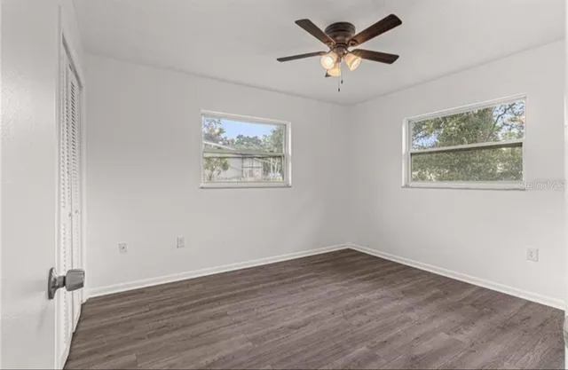 a view of empty room with wooden floor and window