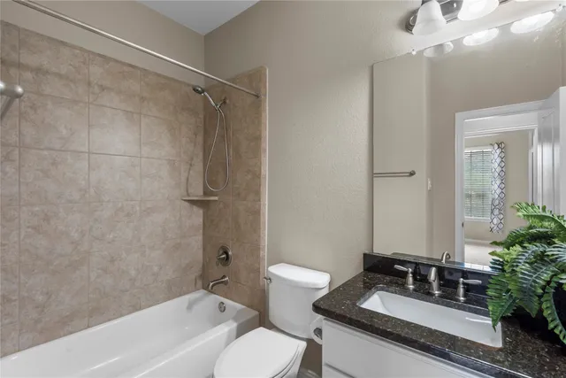 a bathroom with a granite countertop sink a toilet a mirror and shower