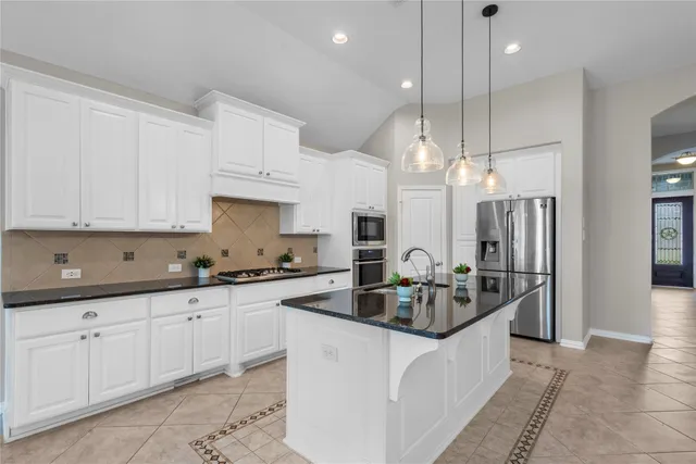 a kitchen with stainless steel appliances granite countertop a sink a stove and a refrigerator