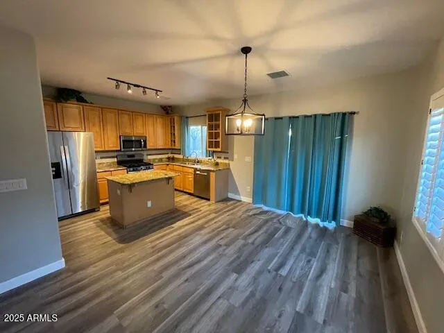 a kitchen with kitchen island wooden floors wooden cabinets a sink and appliances