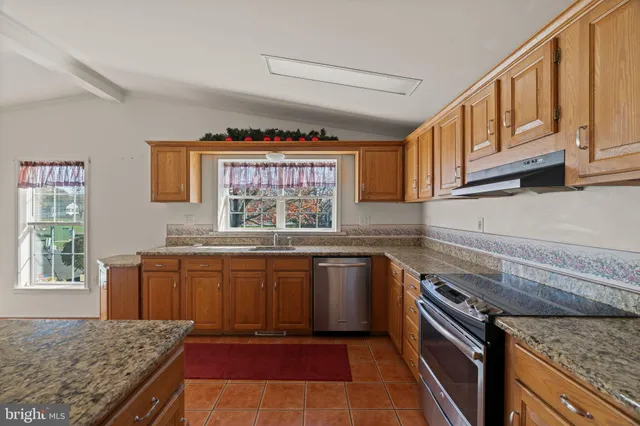 a kitchen with stainless steel appliances granite countertop a stove a sink and a microwave