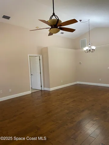 a view of an empty room with chandelier fan