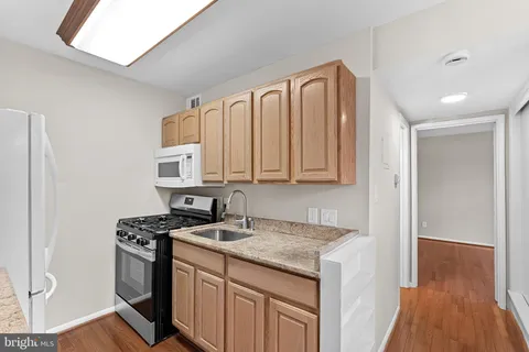 a kitchen with stainless steel appliances granite countertop a stove a sink and a refrigerator with wooden floor