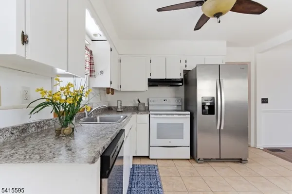 a kitchen with stainless steel appliances granite countertop a sink a refrigerator and a counter space