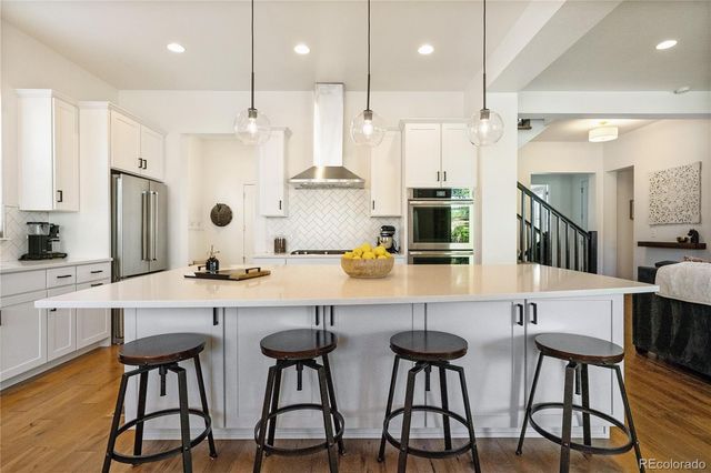 a kitchen with stainless steel appliances kitchen island granite countertop a dining table chairs and white cabinets