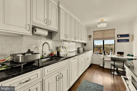 a kitchen with granite countertop a sink a stove and cabinets