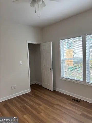 an empty room with wooden floor and windows