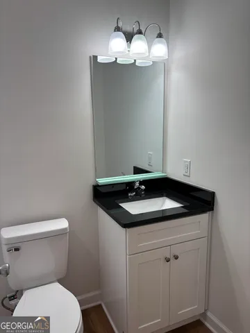 a bathroom with a granite countertop sink and a toilet