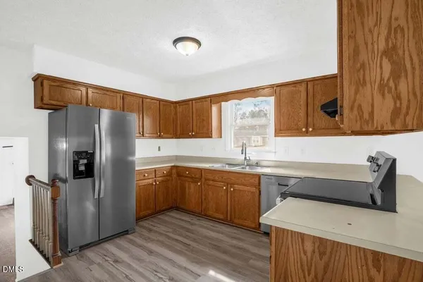 a kitchen with stainless steel appliances a sink cabinets and wooden floor