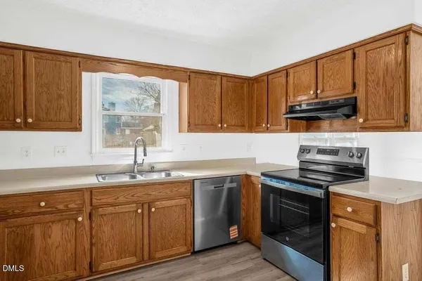 a kitchen with stainless steel appliances granite countertop a sink dishwasher stove and cabinets with wooden floor