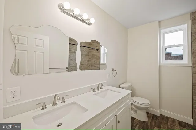 a bathroom with a toilet a sink a mirror and a window
