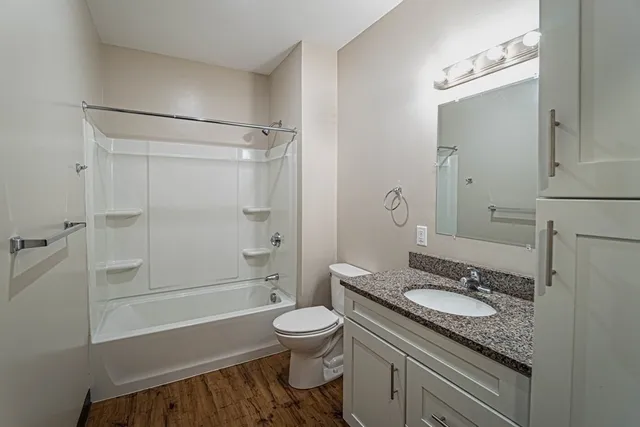 a bathroom with a granite countertop sink toilet a mirror and shower