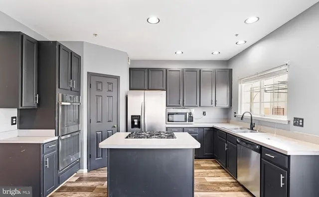 a kitchen with stainless steel appliances a sink stove refrigerator and cabinets