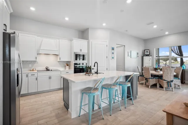 a kitchen with appliances a sink a counter top space and living room view