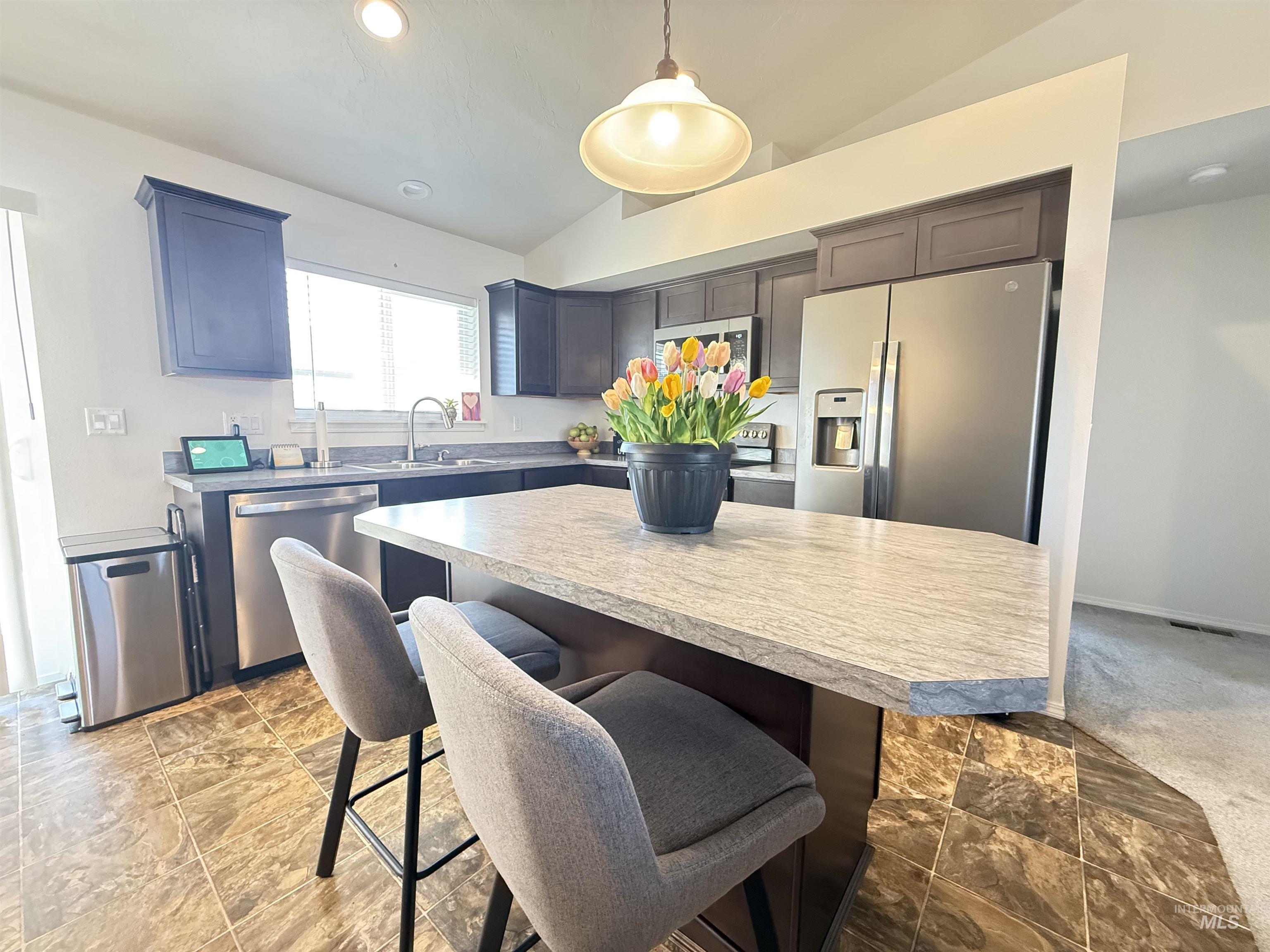 1556 Frontier Drive Lewiston, ID 83501 - Photo 4 of 23 Kitchen featuring a central island with a light-toned countertop, stainless steel appliances, dark cabinetry, and a single basin sink