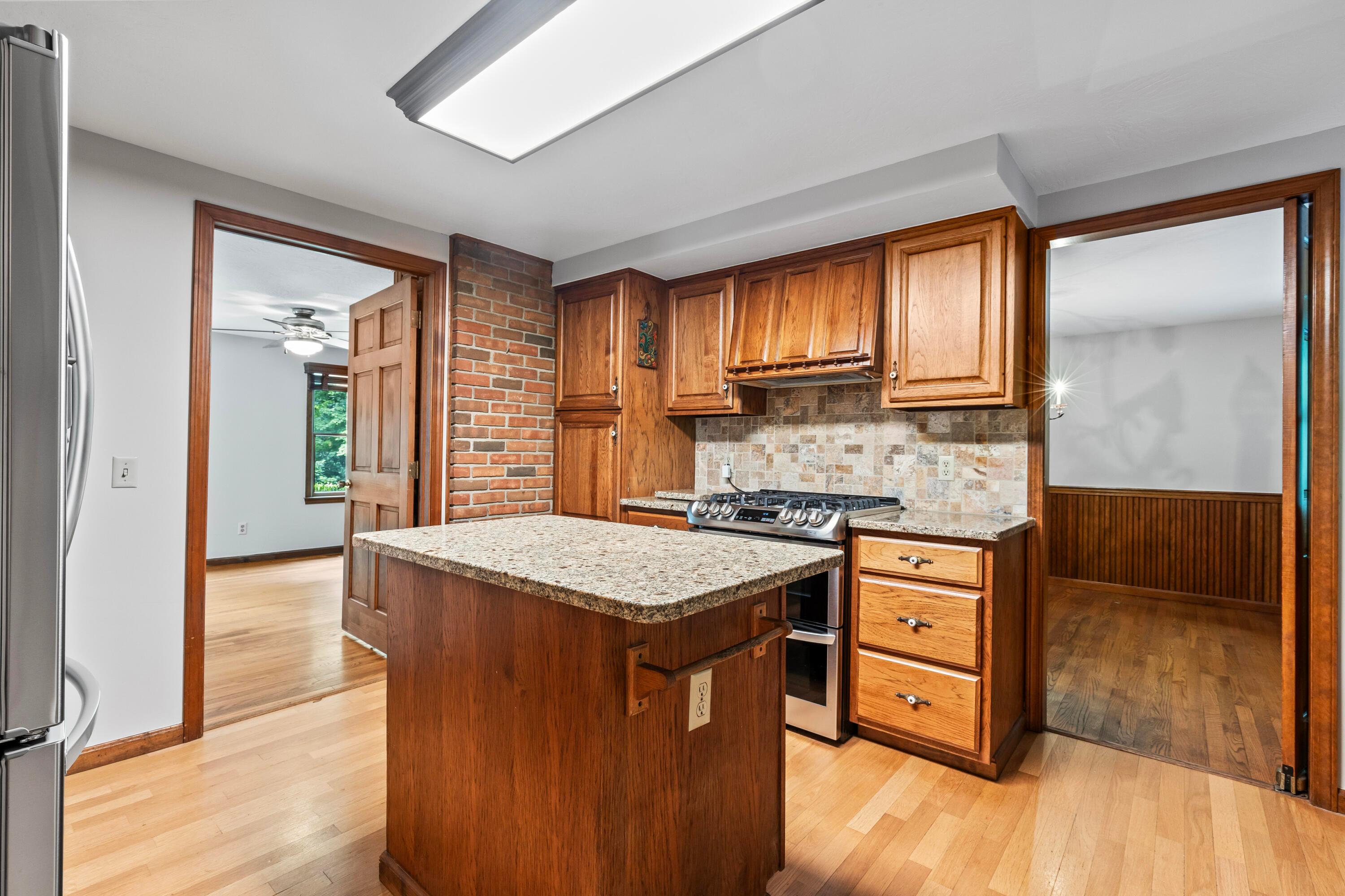 6940 Graham Road Mount Vernon, OH 43050 - Photo 16 of 70 • Hardwood flooring
• Ivory painted walls
• Ceiling light
• Center island with granite
countertops
• Hickory raised panel cabinets
• Wall pantry
• New LG® refrigerator ~ 2021
• New LG® propane gas stove
~ 2021
• LG® dishwasher
• Range hood
• Tumbled marble backsplash
• Double bowl, stainless steel
sink with sprayer & new
faucet
• Door to 3 Season Room
