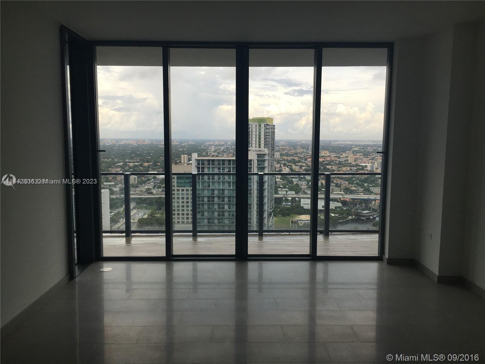 68 Southeast 6th Street, Unit 3510 Miami, FL 33131 - Photo 16 of 19 a view of empty room with wooden floor and city view