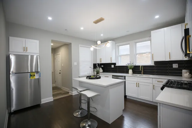 a kitchen with a sink a refrigerator and white cabinets
