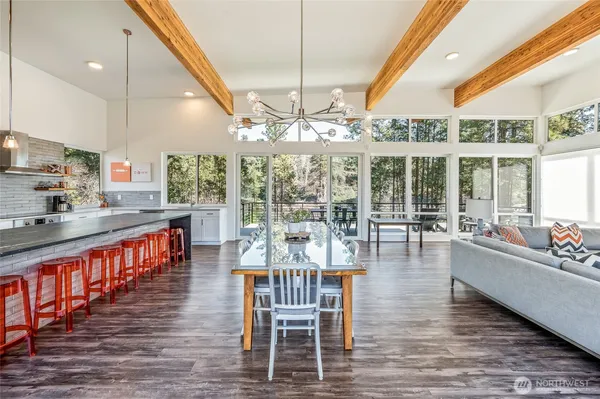 a dining room with wooden floor a chandelier a glass table and chairs