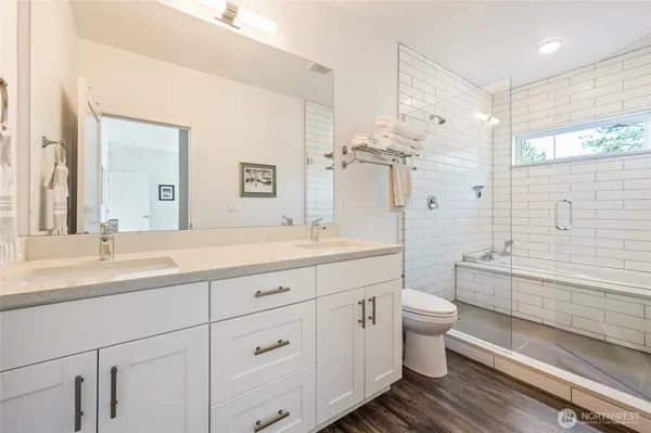a bathroom with a double vanity sink toilet mirror and bathtub