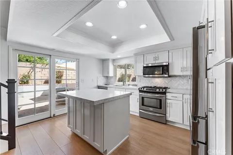 a kitchen with stainless steel appliances granite countertop a stove top oven a sink and a refrigerator