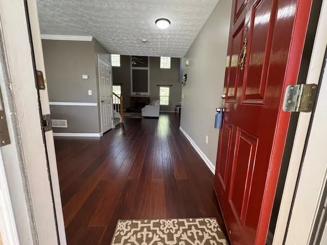 a view of a hallway to a livingroom with wooden floor and staircase