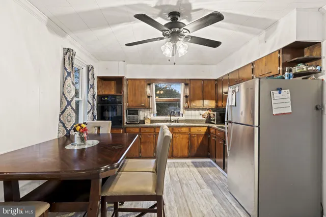 a kitchen with stainless steel appliances granite countertop a refrigerator a sink a stove and chairs with wooden floor