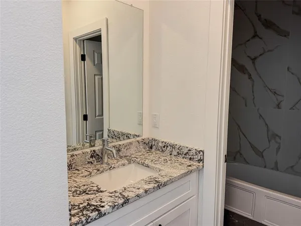 a bathroom with a granite countertop sink and a mirror