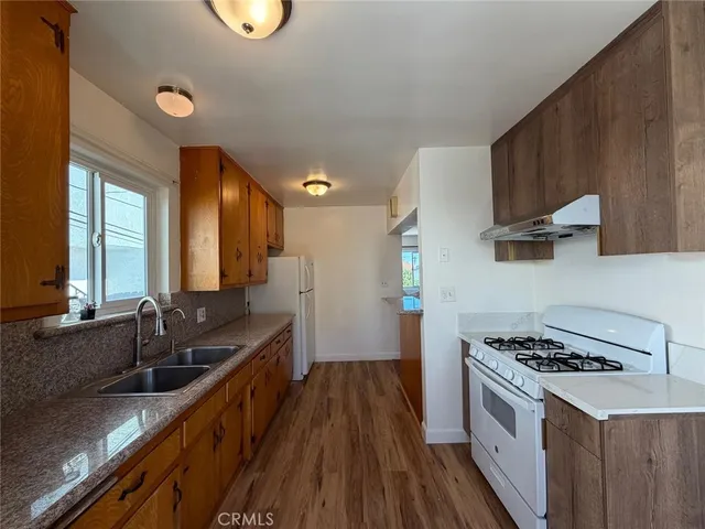 a kitchen with stainless steel appliances a sink stove and wooden floor