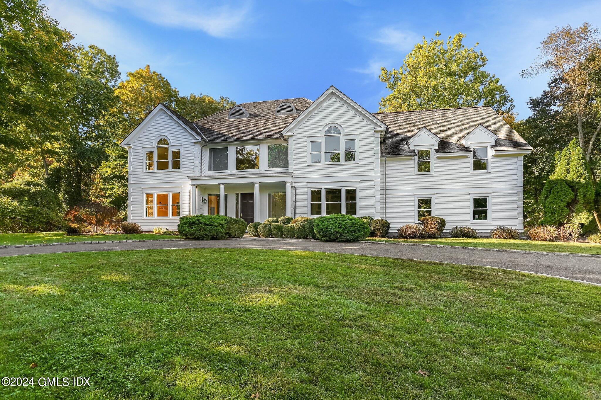 a view of a white house with a big yard and potted plants