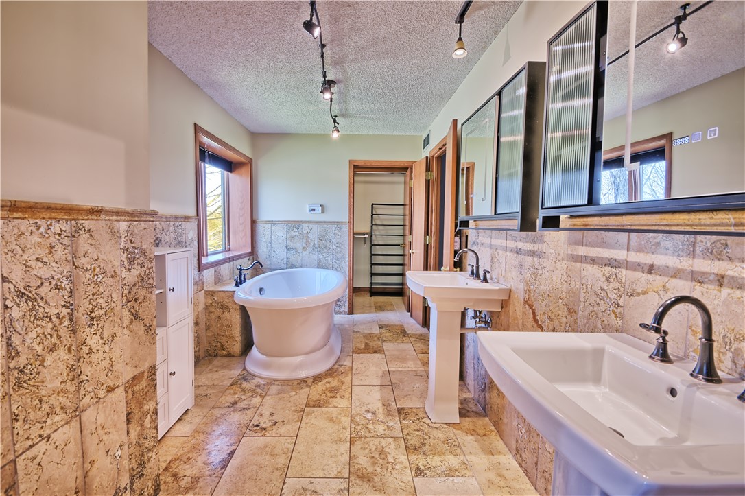 8711 Nicole Lane Springboro, OH 45066 - Photo 45 of 87 This serene bathing area features a luxurious soaking tub and dual pedestal sinks, set against elegant tile work.
